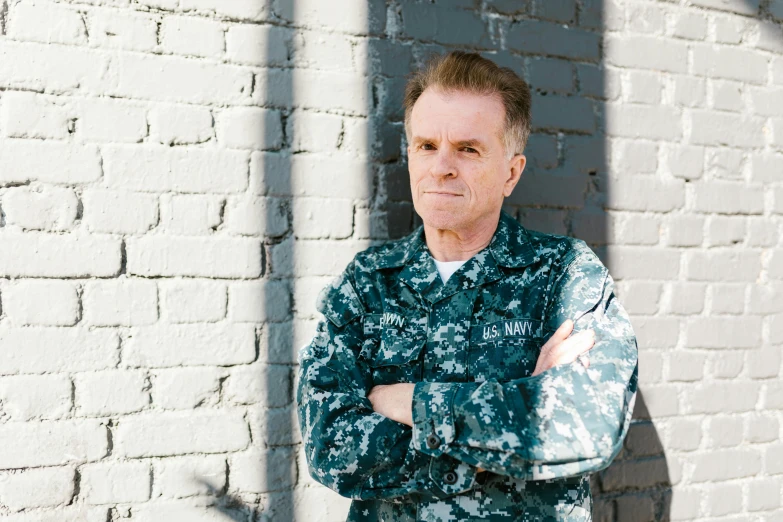 a man standing in front of a brick wall, navy, wearing military outfit, william dafoe, photo illustration