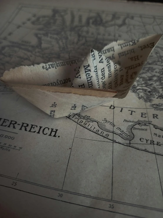 a paper boat sitting on top of a map, set in ww2 germany, real aircrafts references, marischa becker, photograph ”