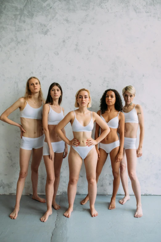 a group of women standing next to each other, inspired by Vanessa Beecroft, unsplash, antipodeans, sport bra and shorts, white porcelain skin, freezing, white wearing