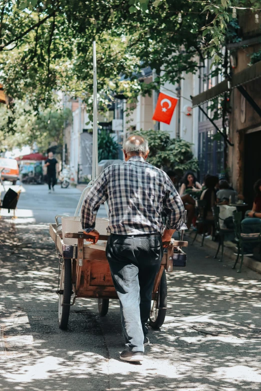 a man pushing a cart down a street, by Niyazi Selimoglu, pexels contest winner, ottoman empire, sunny day, 🚿🗝📝, promo image
