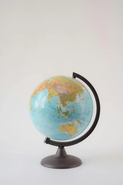 a small globe sitting on top of a table, plain background, jen yoon, high-quality photo, 3/4 front view