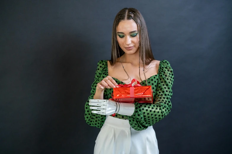 a woman in a green dress holding a red present, by Julia Pishtar, pexels contest winner, robotic bionic technical, wearing a designer top, articulated joints, italian looking emma