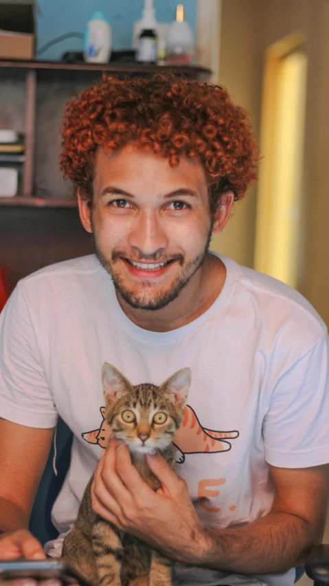 a man sitting at a desk holding a cat, a photo, trending on reddit, he has short curly brown hair, halfbody headshot, eytan zana, curly and short top hair