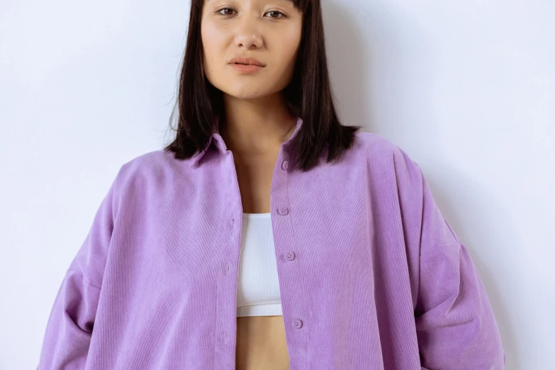 a woman standing in front of a white wall, an album cover, inspired by Kim Tschang Yeul, trending on pexels, gutai group, wearing a purple sweatsuit, bathrobe, button - up shirt, nishihara isao