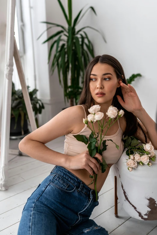 a woman sitting on the floor next to a potted plant, a picture, by Adam Marczyński, trending on pexels, renaissance, wearing a sexy cropped top, pastel roses, portrait sophie mudd, standing elegantly