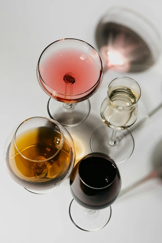 a group of wine glasses sitting on top of a table, on a pale background, mixing drinks, detailed product image, multiple stories