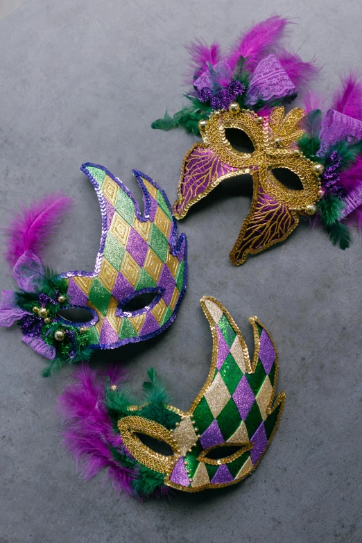 a couple of mardi gras masks laying on top of each other, top-down shot, ((purple)), product shot, exterior shot