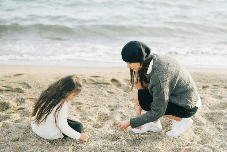 a mother and daughter playing in the sand at the beach, by Arabella Rankin, pexels contest winner, symbolism, winter season, fashionable, videogame still, gif