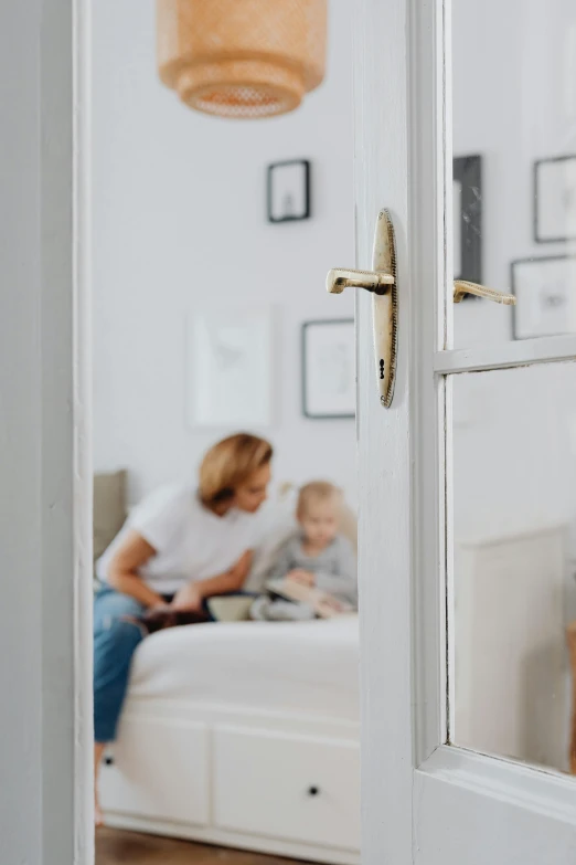 a woman sitting on top of a bed next to a child, pexels contest winner, opening door, brass plated, detail shot, open plan
