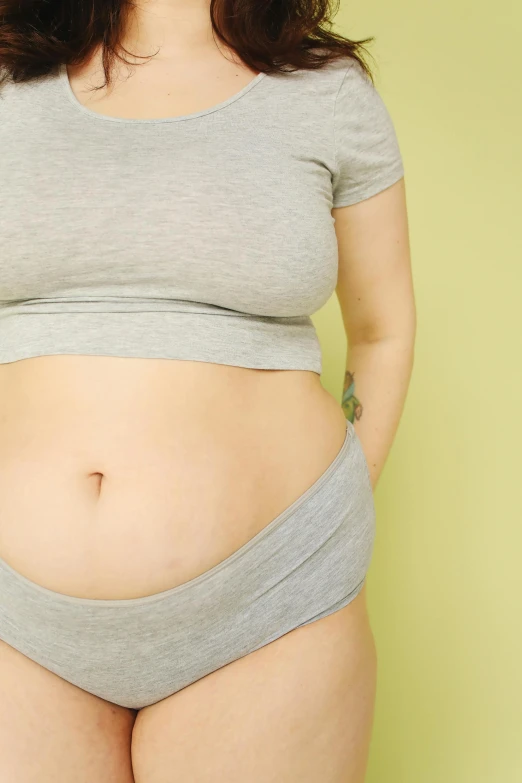 a woman in a gray shirt posing for a picture, a digital rendering, by Nicolette Macnamara, unsplash, her belly button is exposed, green body, thick outline, surgery