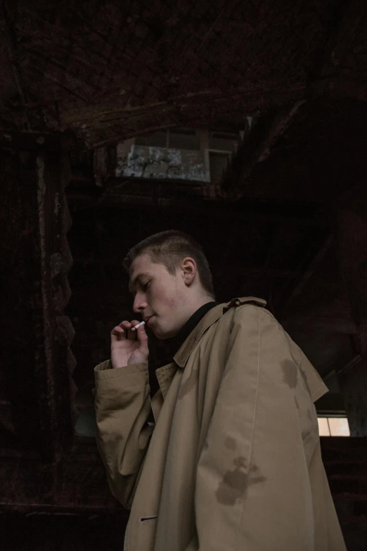 a man in a raincoat talking on a cell phone, an album cover, unsplash, yung lean, in a dark warehouse, he is wearing a brown sweater, ((portrait))