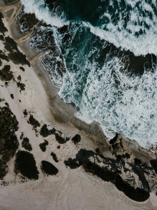 a large body of water next to a sandy beach, pexels contest winner, mid air shot, intense details, stormy coast, trending on vsco