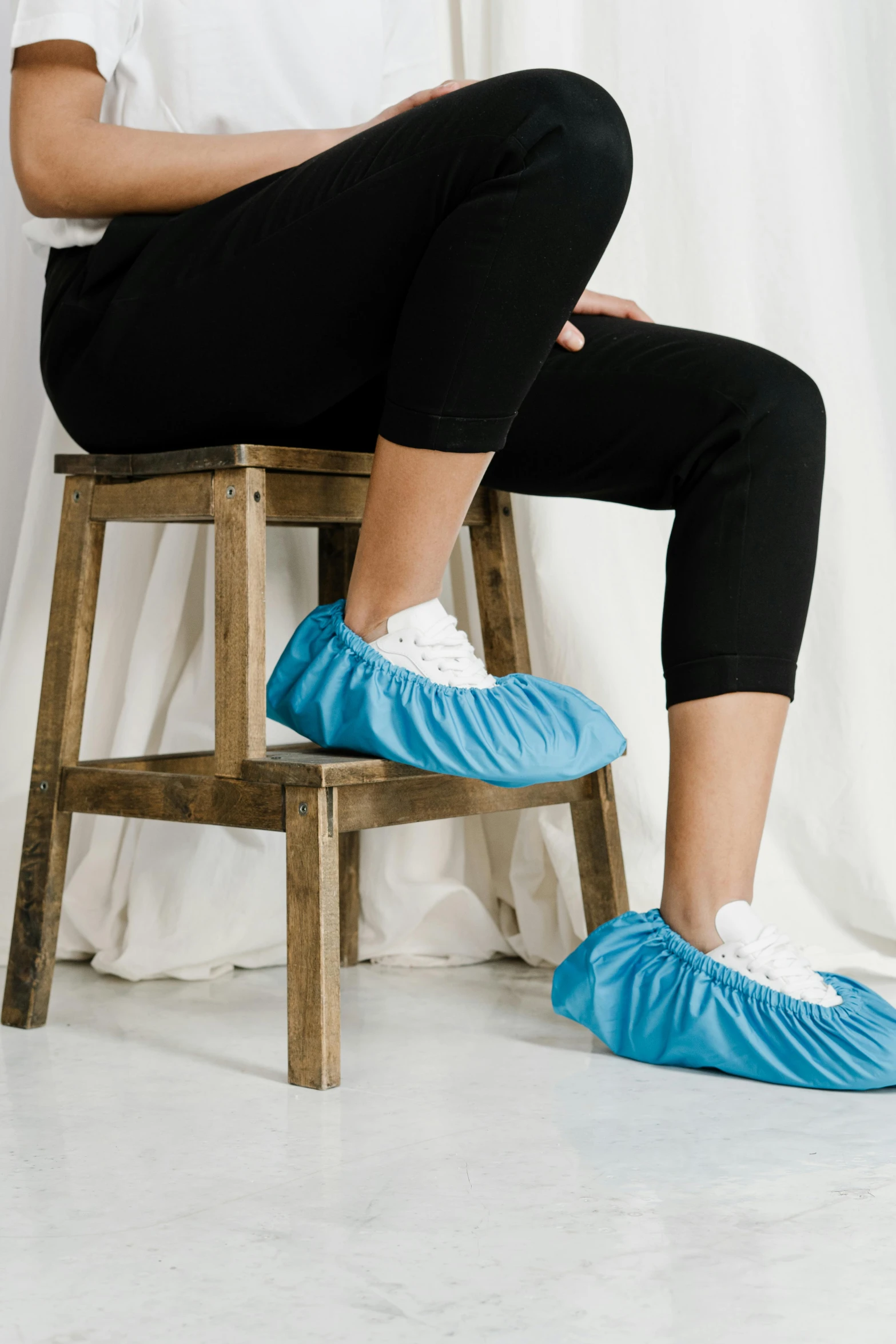 a woman sitting on top of a wooden stool, blue shoes, made of lab tissue, thumbnail, scrubs
