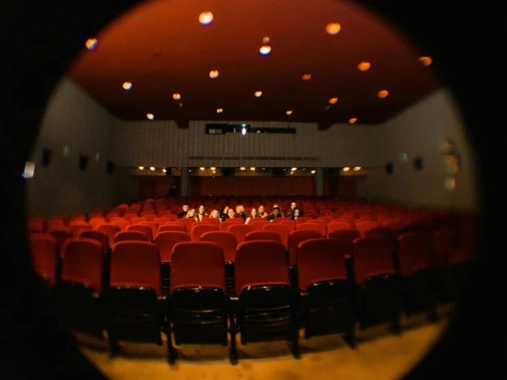 an empty auditorium with rows of red chairs, a picture, unsplash, process art, cinémascope, fisheye lens photo, group of people in a dark room, wes anderson film