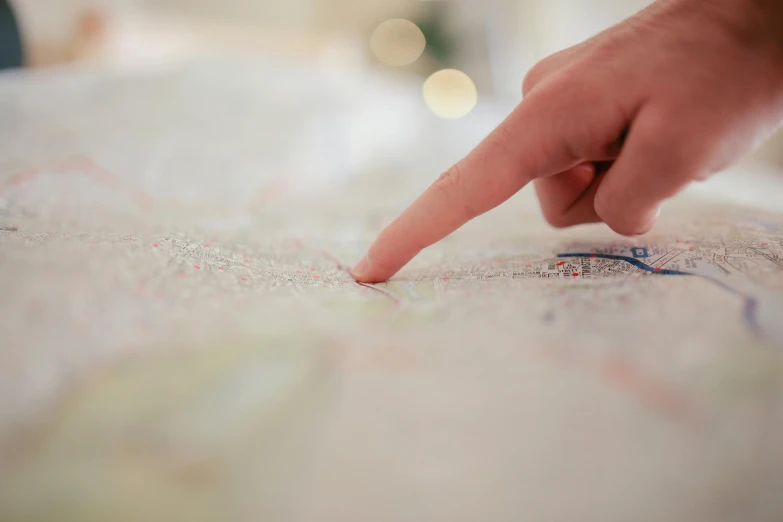 a person pointing at a map on a table, by Nick Fudge, unsplash, close-up of thin soft hand, walking, bespoke, soft light