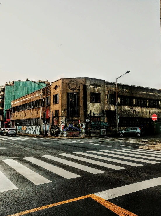 a street filled with lots of traffic next to tall buildings, an album cover, pexels contest winner, graffiti, old abandoned building, brutalist aztec architecture, panoramic, aged and weathered