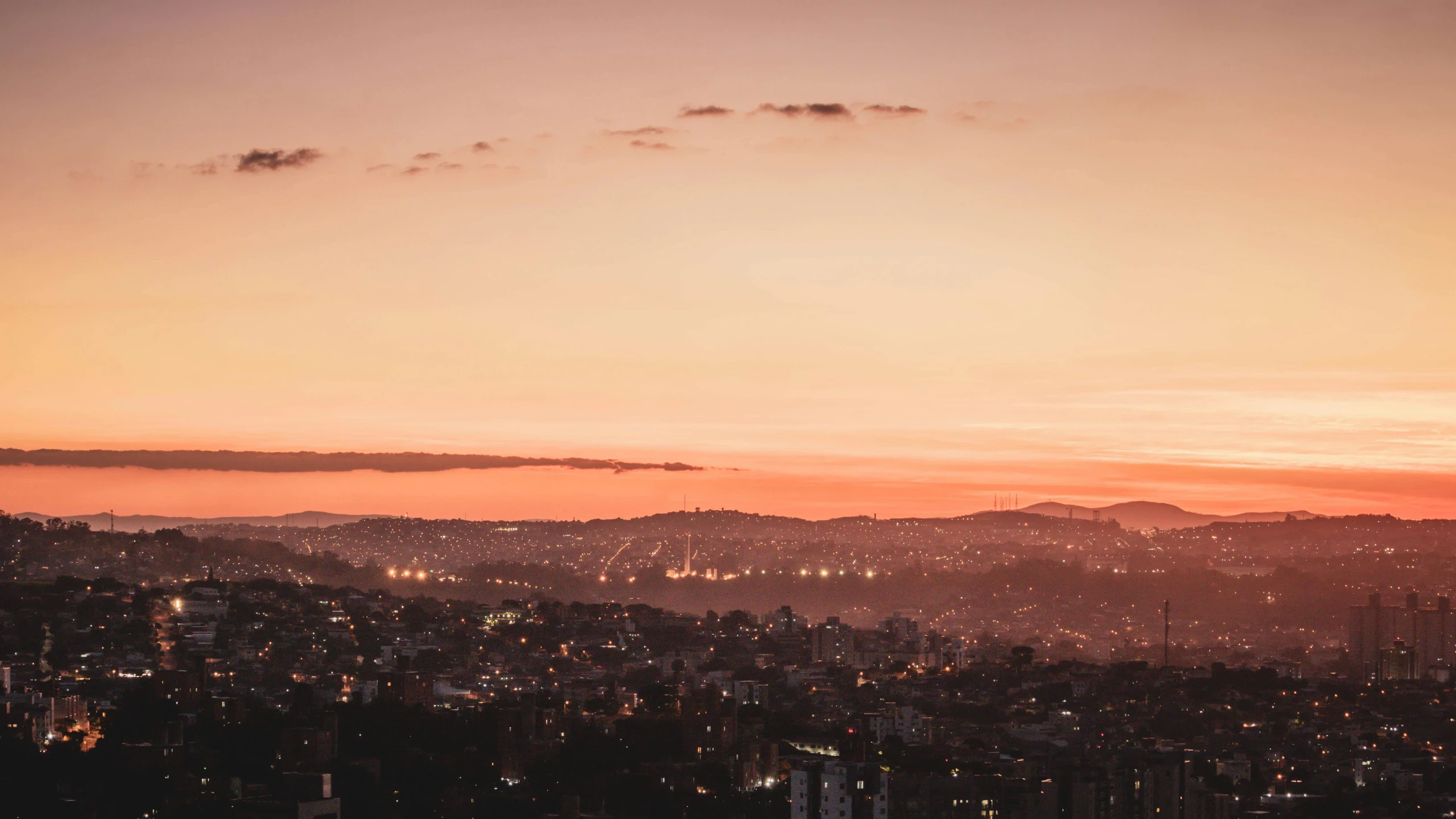 a view of a city from the top of a hill, by Alejandro Obregón, pexels contest winner, pink sunset, muted lights, desktop background, colombia