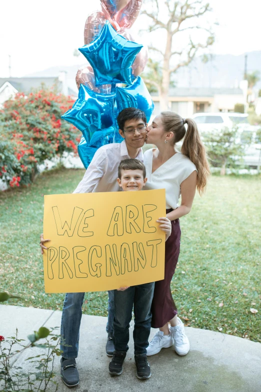 a man and woman standing next to each other holding a sign, by Ellen Gallagher, pexels, happening, pregnant, square, celebration, asian male