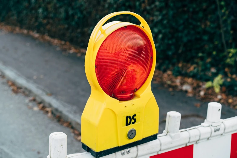 a yellow traffic light sitting on top of a red and white barricade, by David Donaldson, unsplash, tactile buttons and lights, wearing hi vis clothing, ds, detailed information