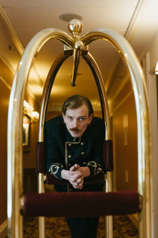 a man that is sitting in a chair, a portrait, by Julia Pishtar, unsplash, art nouveau, grand budapest hotel, chairlifts, officer, high quality photo