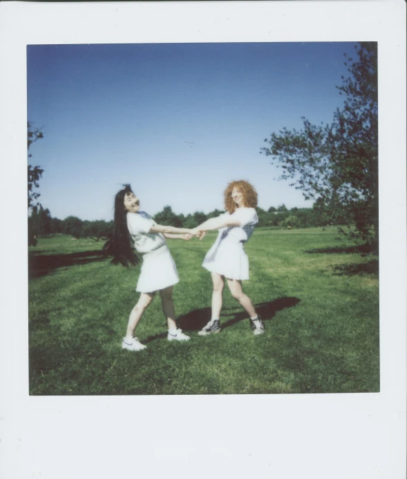 a couple of women standing on top of a lush green field, a polaroid photo, inspired by Nan Goldin, unsplash, kitsch movement, her hair is white, lunging at camera :4, melanie martinez, on a pale background