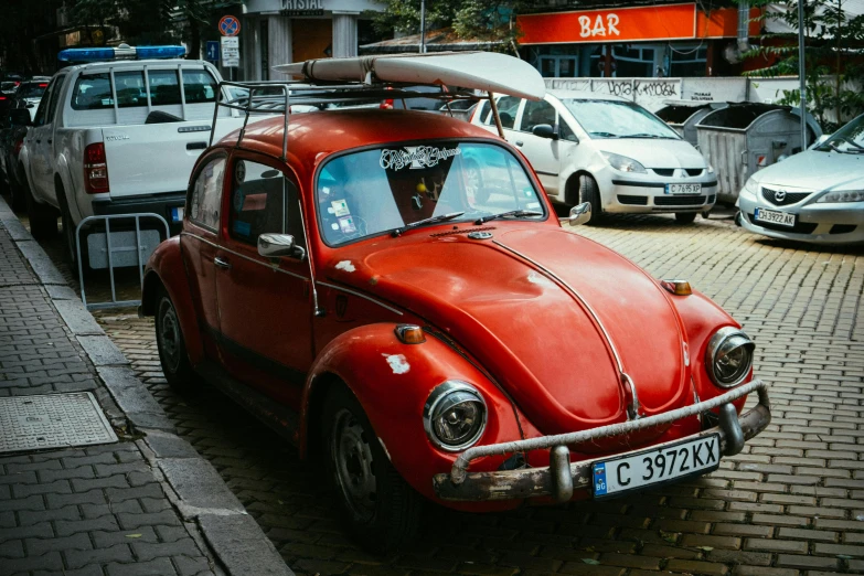 a red car with a surfboard on top of it, by Adam Marczyński, pexels contest winner, horned beetle, square, eastern european origin, 🚿🗝📝