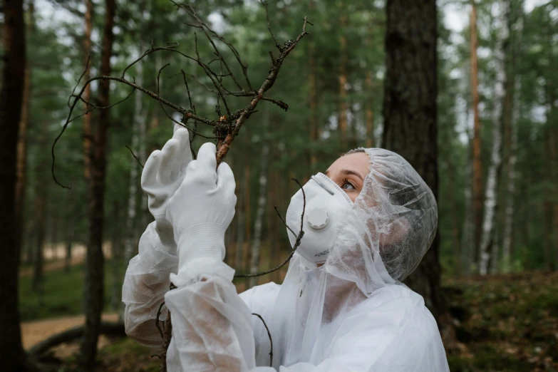 a woman holding a branch in a forest, an album cover, by Emma Andijewska, pexels contest winner, environmental art, staff wearing hazmat suits, inspect in inventory image, wearing lab coat, beauty is a virus