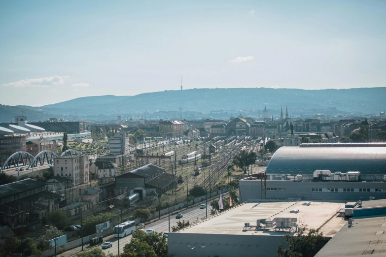 a view of a city from the top of a building, budapest street background, tech city in the background, chesterfield, sunfaded