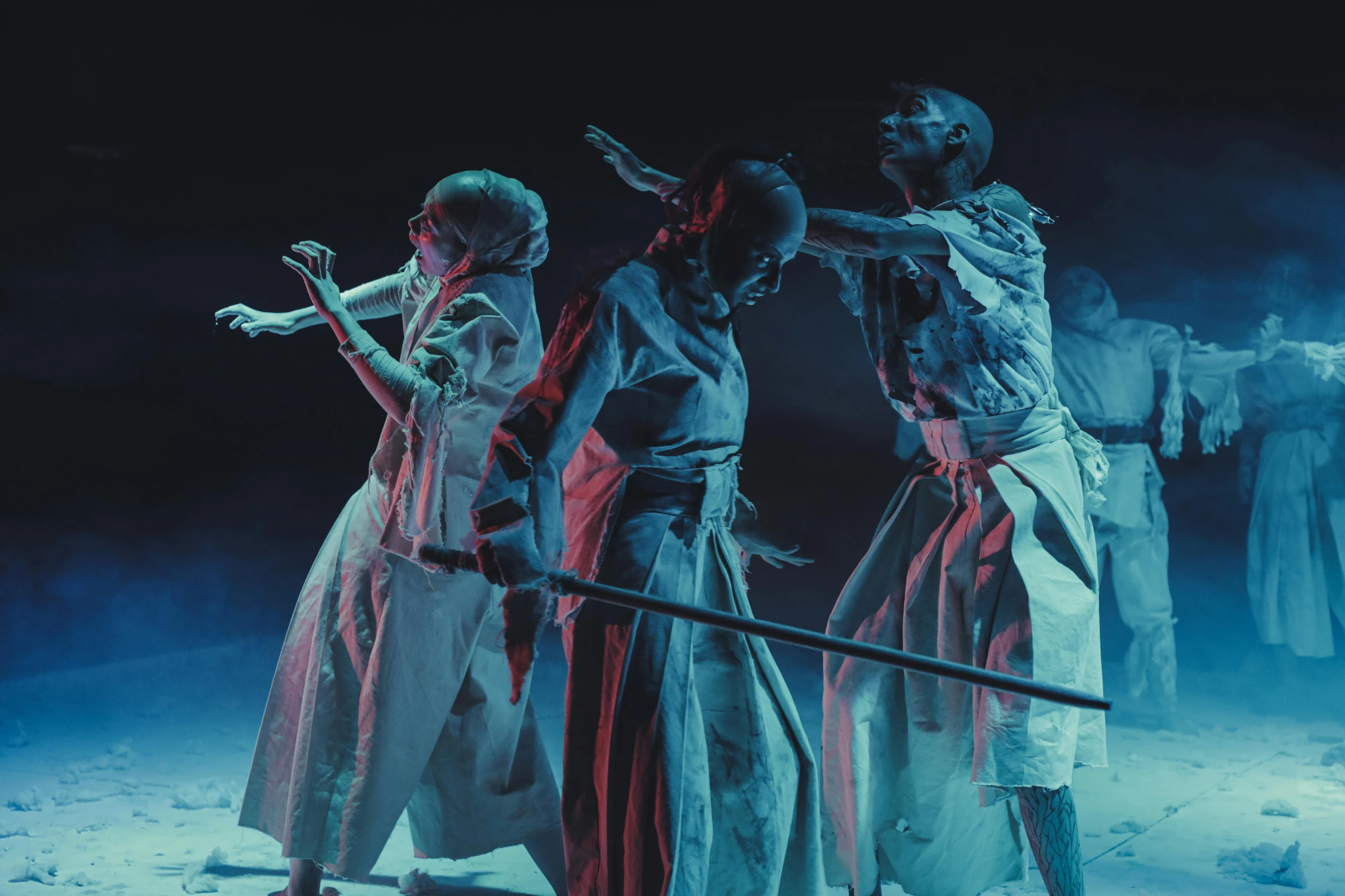 a group of people standing on top of a snow covered ground, by Adam Marczyński, pexels contest winner, ukiyo-e, violent zombie dance, 3 actors on stage, blue tunic and robes, teamlab