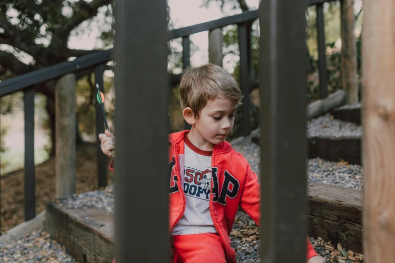 a little boy that is sitting on some stairs, unsplash, wearing a track suit, wearing a red lumberjack shirt, standing astride a gate, kids playing