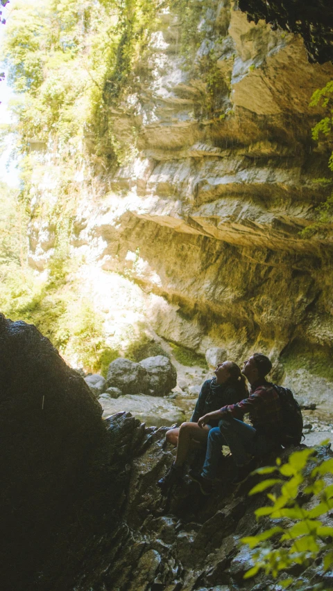 a couple of people that are sitting on some rocks, les nabis, overgrown stone cave, instagram photo, thumbnail, full frame image