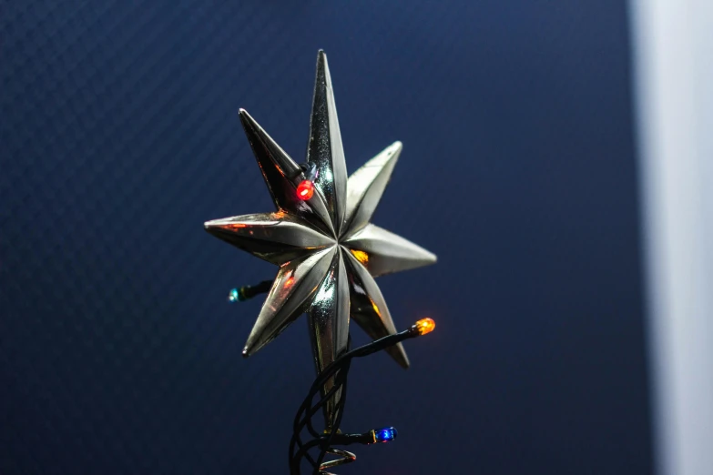 a christmas tree topper with a star on it, by Niko Henrichon, unsplash, photorealism, modeled lighting, angled shot, silver dechroic details, multi - coloured