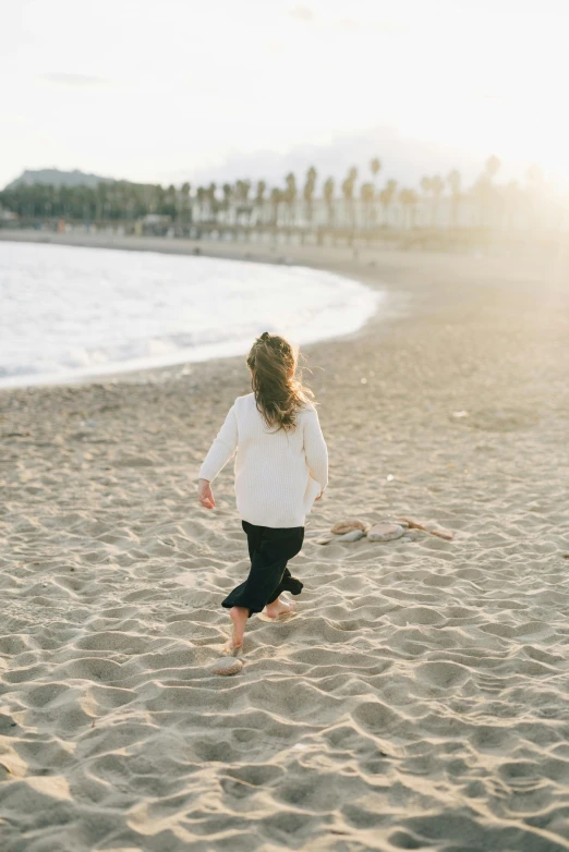 a little girl running on a beach near the ocean, by Lucia Peka, unsplash, minimalism, soft sun lights, the city of santa barbara, instagram post, hair