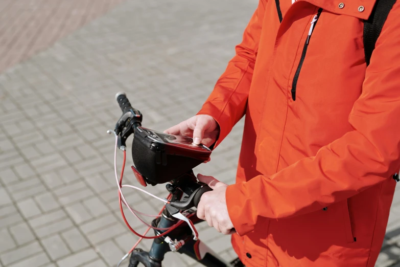 a man in an orange jacket riding a bike, a picture, pexels, scanning items with smartphone, charging plug in the chest, avatar image, high resolution image