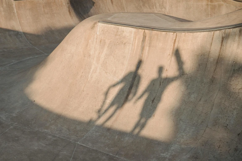 a man riding a skateboard up the side of a ramp, by Jan Kupecký, pexels contest winner, concrete art, faces covered in shadows, two people, light toned, drone photo