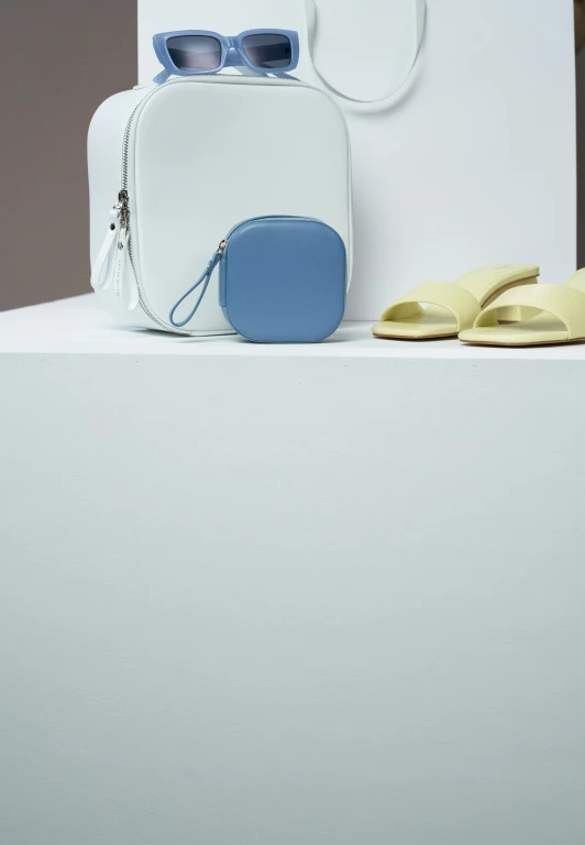 a white suitcase sitting on top of a table next to a pair of yellow sandals, inspired by Bauhaus, ice blue, detail shot, leather pouch, (night)