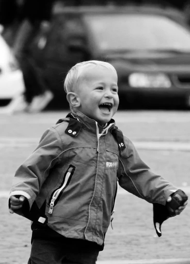 a little boy that is standing on a skateboard, a black and white photo, pexels, smiling laughing, wearing a flying jacket, zoomed in, happy with his mouth open