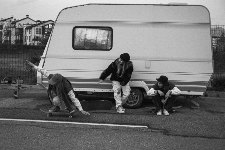 a group of people riding skateboards next to a camper, a black and white photo, by Matija Jama, broken down, thugs, maintenance, profile pic