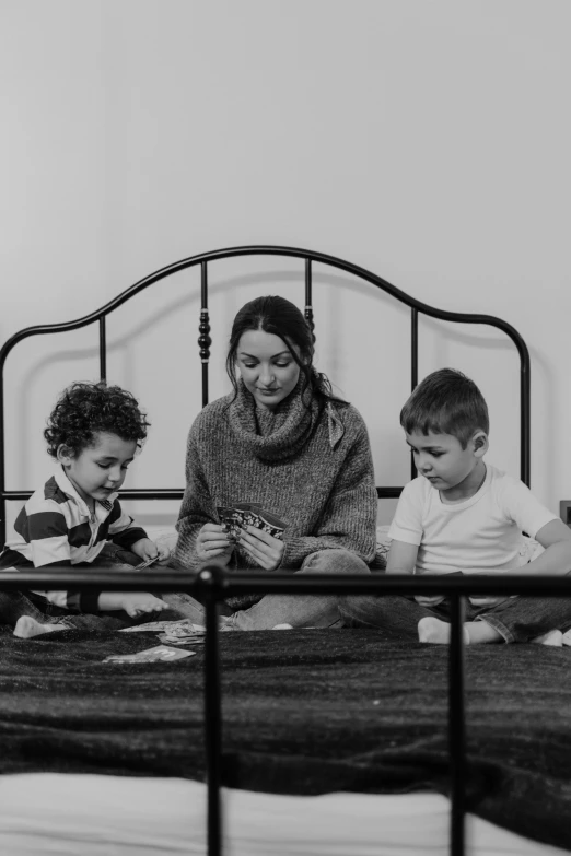 a woman and two children sitting on a bed, a black and white photo, card game, shot on sony a 7, trending photo, instagram photo