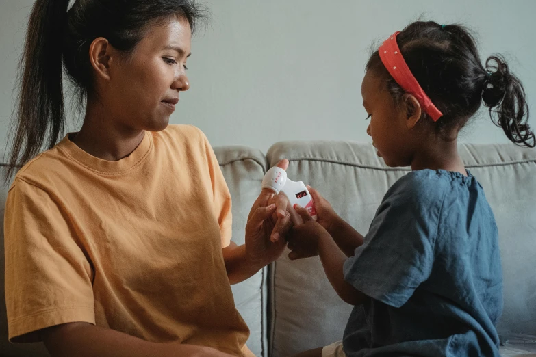 a woman and a little girl sitting on a couch, first aid kit, manuka, varying ethnicities, over the shoulder