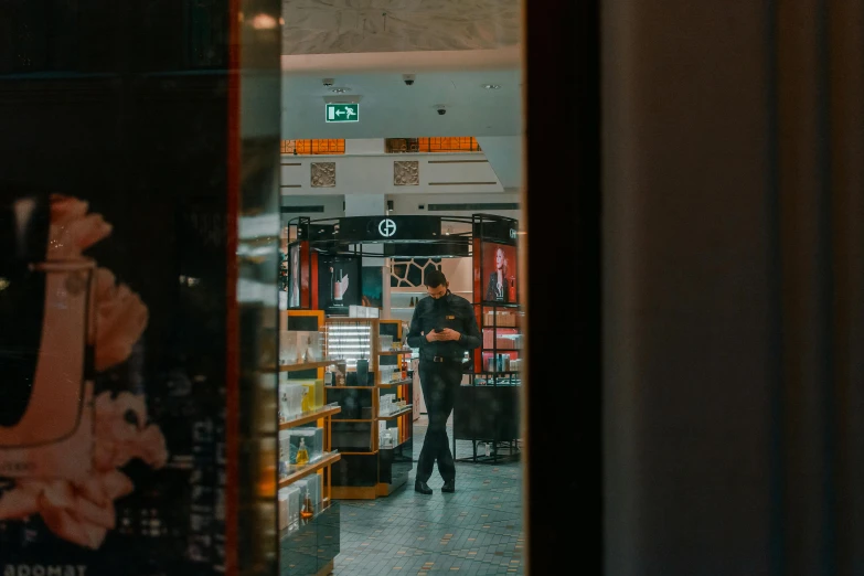 a man standing in front of a book store, pexels contest winner, mirror hallways, orange and black tones, lachlan bailey, regal fast food joint