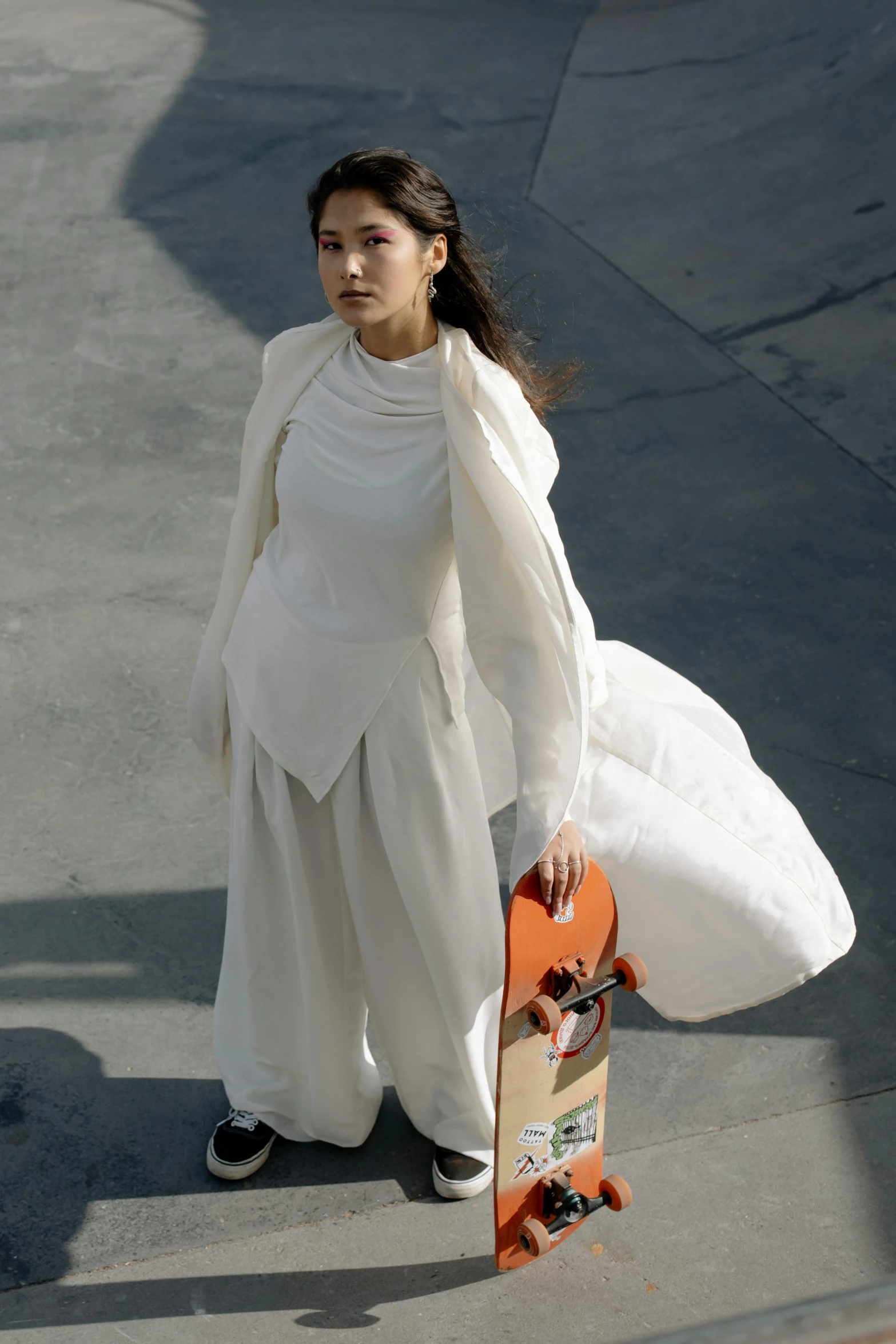a woman in a white dress holding a skateboard, inspired by Marina Abramović, gutai group, dressed with long fluent clothes, fluid bag, jamie chung, white and orange