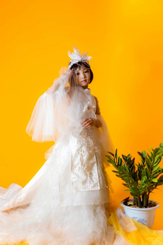 a woman in a wedding dress standing next to a potted plant, an album cover, inspired by Otake Chikuha, unsplash, rococo, in front of an orange background, angelic pretty, haute couture fashion shoot, children's