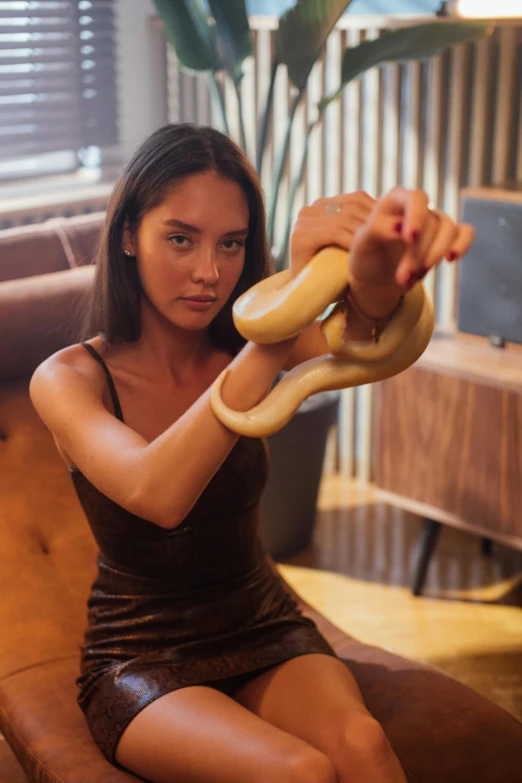 a woman sitting on a couch holding a snake, by Adam Marczyński, instagram, arm wrestling, kung fu, sleek hands, 1 8 yo