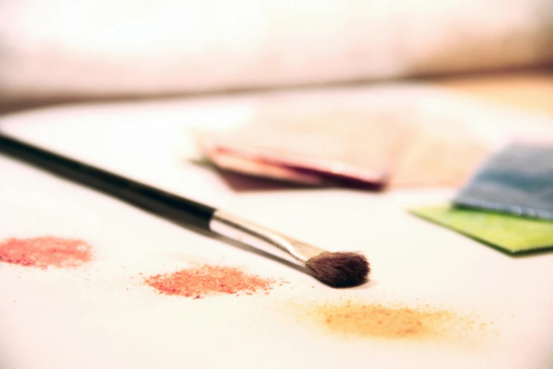 a close up of a makeup brush on a table, a photorealistic painting, trending on pexels, light watercolour, warm saturated colours, dust motes in air, art station ”