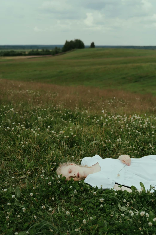 a woman laying on top of a lush green field, an album cover, by Attila Meszlenyi, romanticism, in russia, ignant, cottagecore, elle fanning