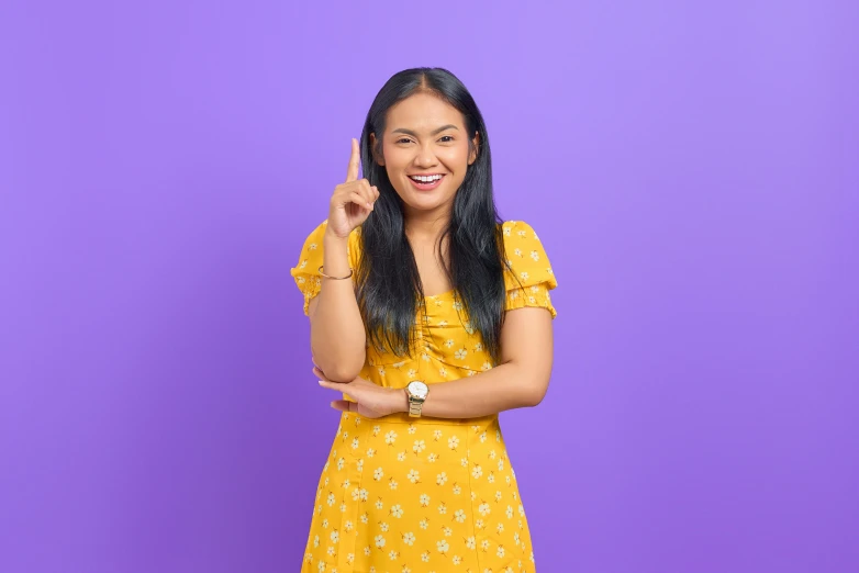 a woman in a yellow dress posing for a picture, inspired by helen huang, trending on pexels, pointing index finger, purple themed, basic background, half asian