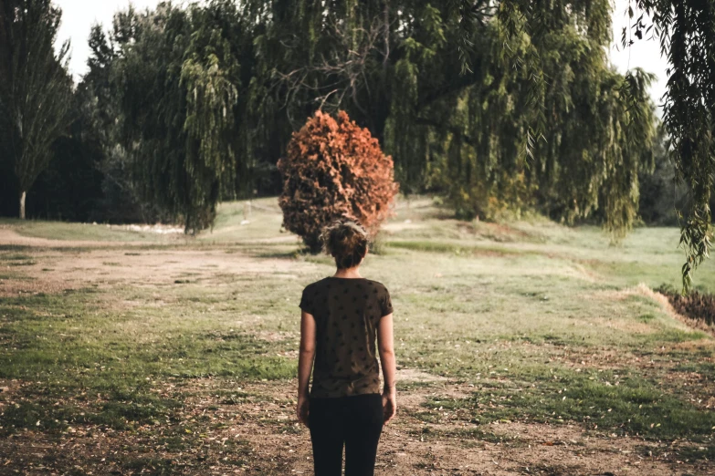a woman walking down a dirt road next to a tree, an album cover, by Anna Boch, unsplash contest winner, environmental art, growth on head, ignant, person made of tree, at a park
