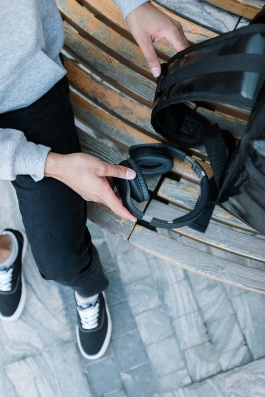 a person sitting on top of a wooden bench, wearing modern headphone, black plastic, graphical, anthracite