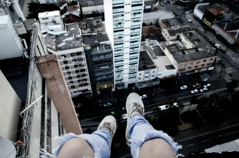 a person standing on top of a tall building, by Niko Henrichon, pexels contest winner, realism, her foot sticking out, in sao paulo, sitting down, falling buildings